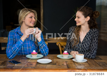 Beautiful female friends having coffee while talking in cafeteria 31878684