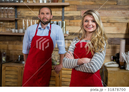Smiling female barista with male colleague in coffee shop Smiling female barista with male colleague in coffee shop 31878700