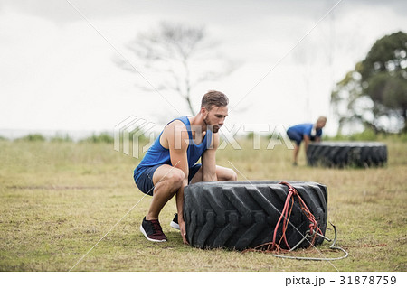 Fit woman flipping a tire during obstacle course Fit woman flipping a tire during obstacle course 31878759