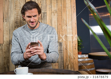 Man using smart phone at table in coffee shop Man using smart phone at table in coffee shop 31878879