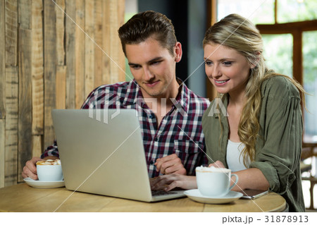 Smiling couple using laptop at table in coffee shop 31878913