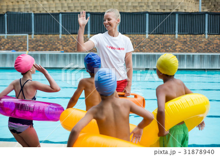 Lifeguard instructing children at poolside 31878940