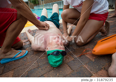 Lifeguards helping senior man at poolside 31879235