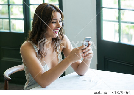 Smiling woman using mobile phone in restaurant 31879266