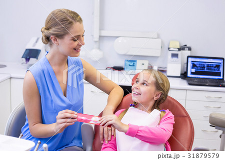 Mother giving tooth brush to daughter at dental clinic 31879579