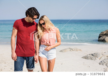 Couple wearing sunglasses while standing at beach 31879681