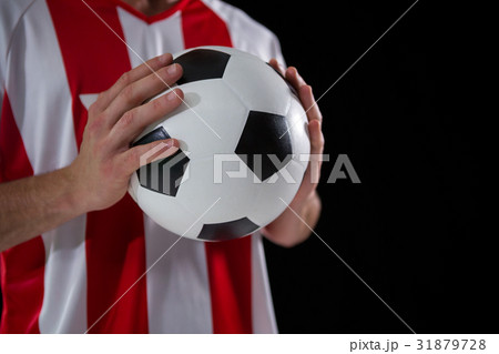 Mid-section of football player holding football with both hands Mid-section of football player holding football with both hands 31879728