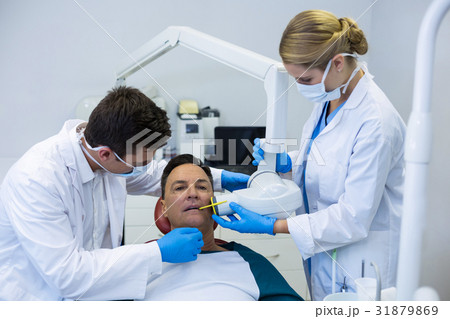 Dentists examining a male patient with tools Dentists examining a male patient with tools 31879869