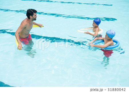 Coach and students interacting with each other in swimming pool Coach and students interacting with each other in swimming pool 31880042