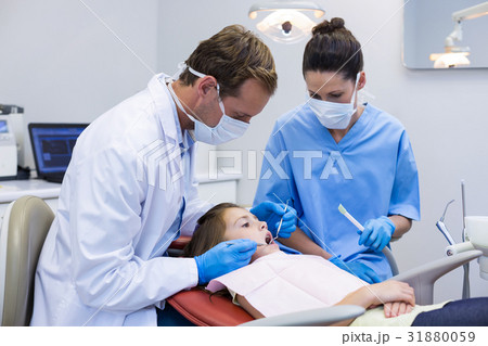 Dentist examining a young patient with tools 31880059