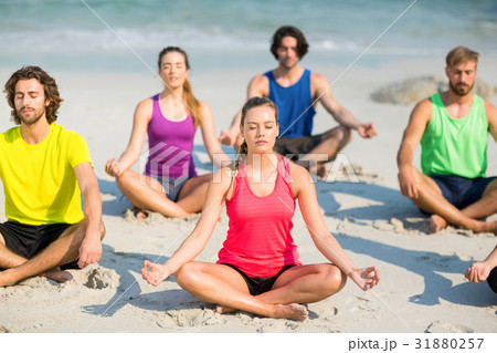 Friends meditating in lotus position on shore 31880257