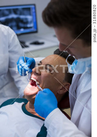 Dentists examining a male patient with tools Dentists examining a male patient with tools 31880820