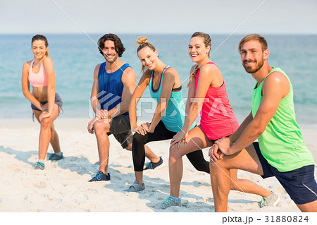 Friends stretching on shore at beach Friends stretching on shore at beach 31880824