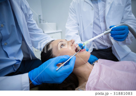Dentist examining a female patient with tools 31881083