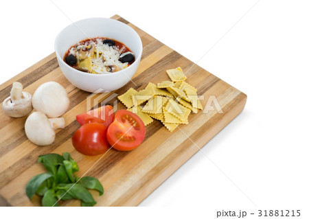 Cooked food in bowl by ravioli and vegetables on cutting board 31881215