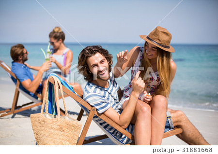 Romantic young couples sitting on deck chairs at beach 31881668