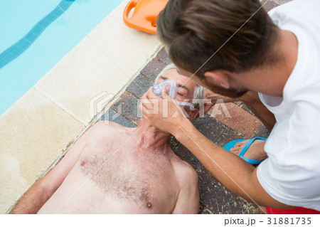 Lifeguard putting oxygen mask to senior man 31881735