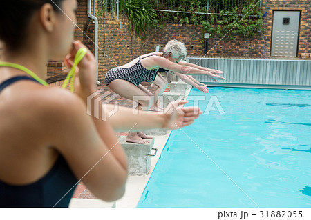 Female trainer whistling while senior women diving into pool 31882055