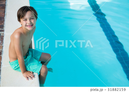 Smiling boy sitting at poolside Smiling boy sitting at poolside 31882159