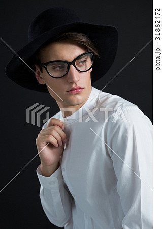 Androgynous man in hat posing with hand on collar Androgynous man in hat posing with hand on collar 31882472