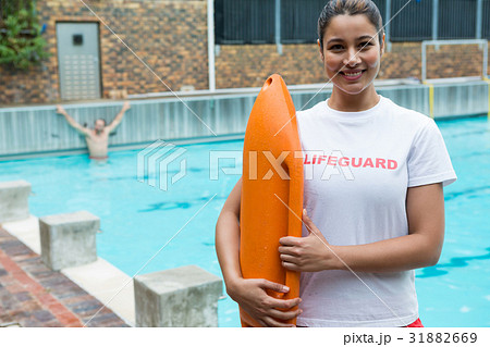 Lifeguard standing with rescue buoy at poolside Lifeguard standing with rescue buoy at poolside 31882669