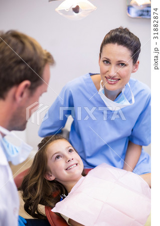 Smiling dentists interacting with young patient 31882874
