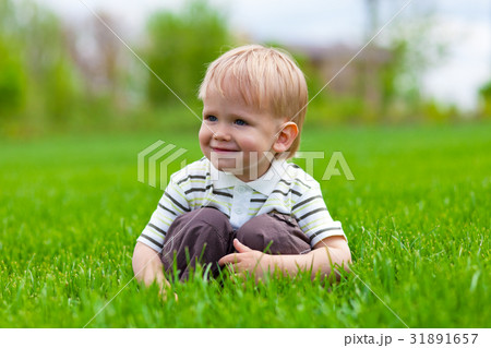 Smiling little boy sitting in fresh grass 31891657
