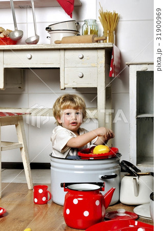Adorable small child sits in kitchen inside a pan Adorable small child sits in kitchen inside a pan 31900969