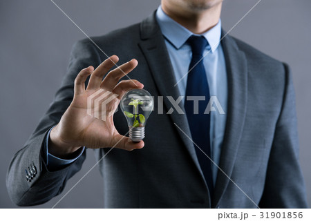 Businessman holding lamp in green environment 31901856