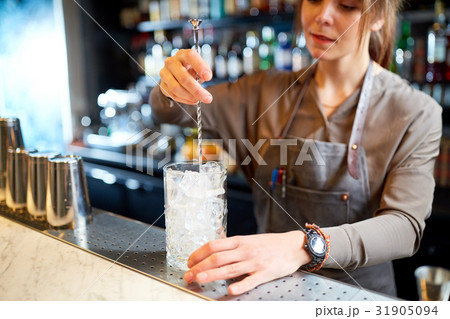 bartender with cocktail stirrer and glass at bar 31905094