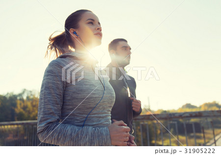 happy couple with earphones running outdoors happy couple with earphones running outdoors 31905222