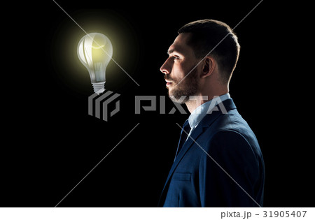 businessman looking at lightbulb over black businessman looking at lightbulb over black 31905407