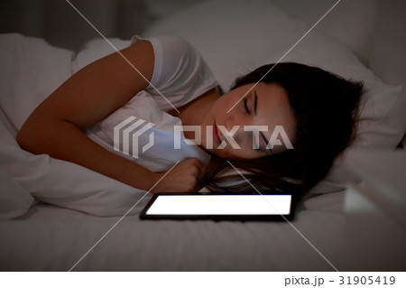 woman with tablet pc sleeping in bed at night woman with tablet pc sleeping in bed at night 31905419