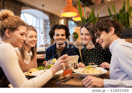 friends with smartphone eating at restaurant friends with smartphone eating at restaurant 31905490