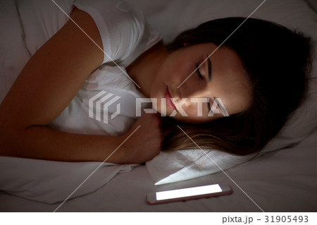woman with smartphone sleeping in bed at night woman with smartphone sleeping in bed at night 31905493