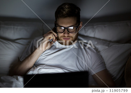 man with laptop calling on smartphone at night man with laptop calling on smartphone at night 31905799