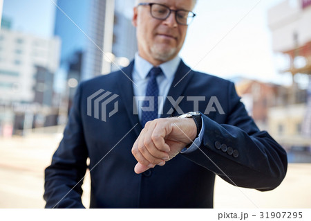 senior businessman with wristwatch on city street senior businessman with wristwatch on city street 31907295