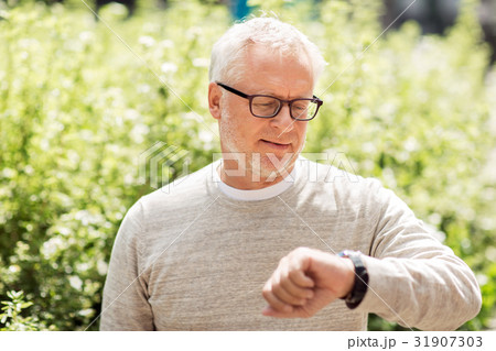 senior man checking time on his wristwatch senior man checking time on his wristwatch 31907303