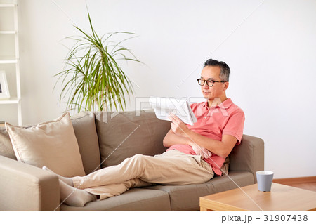 happy man in glasses reading newspaper at home 31907438