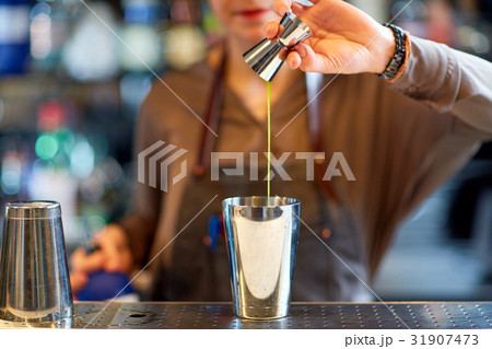 bartender with cocktail shaker and jigger at bar 31907473