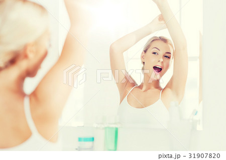 woman yawning in front of mirror at bathroom 31907820
