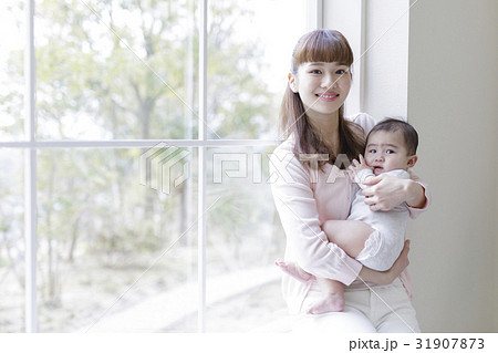 窓辺で赤ちゃんを抱っこする母親 窓辺で赤ちゃんを抱っこする母親 31907873