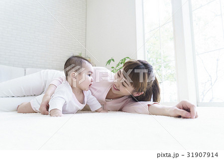 カーペットの上に寝そべる赤ちゃんと母親の写真素材
