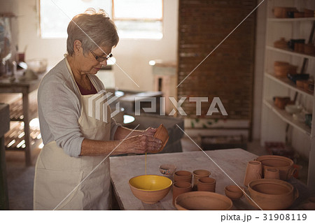 Female potter pouring watercolor in bowl 31908119