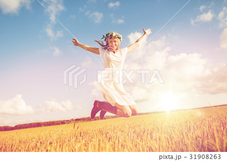 happy woman in wreath jumping on cereal field 31908263