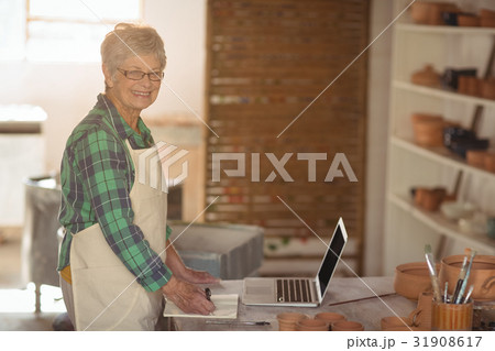 Portrait of female potter making note from laptop Portrait of female potter making note from laptop 31908617