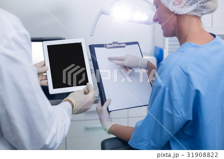 Dentist and dental assistant working on digital tablet Dentist and dental assistant working on digital tablet 31908822