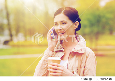 smiling woman with smartphone and coffee in park smiling woman with smartphone and coffee in park 31909236