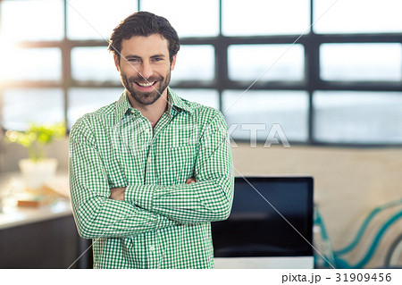 Business executive standing with arms crossed in office 31909456