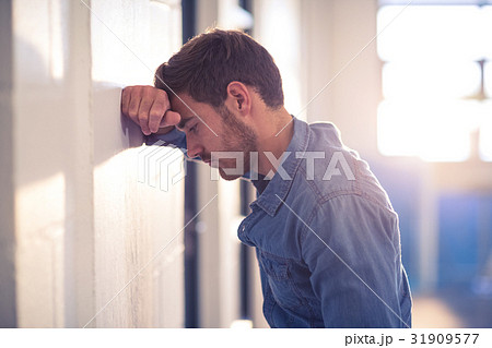 Tired businessman leaning on wall Tired businessman leaning on wall 31909577